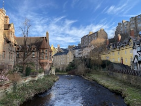brown concrete building beside river under blue sky during daytime