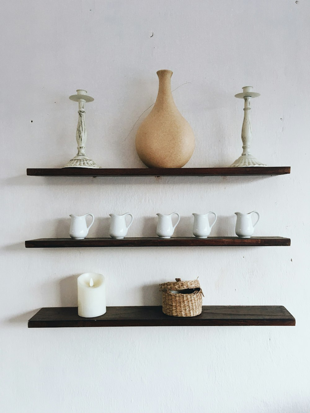 white and brown ceramic vase on white wooden shelf
