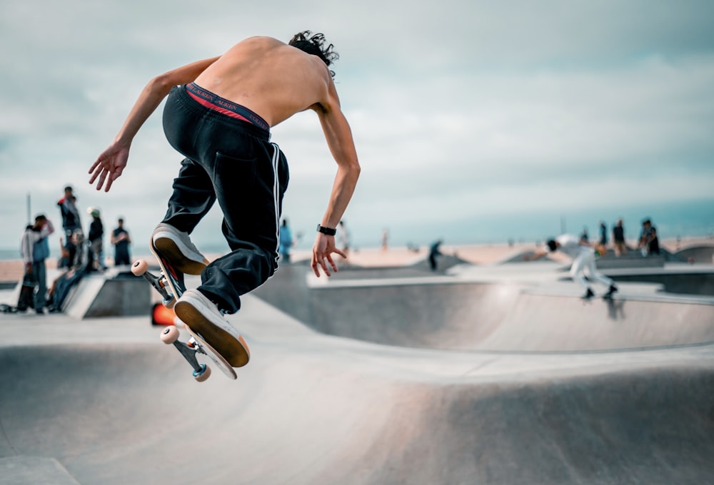 man in black tank top and blue denim jeans doing skateboard stunts
