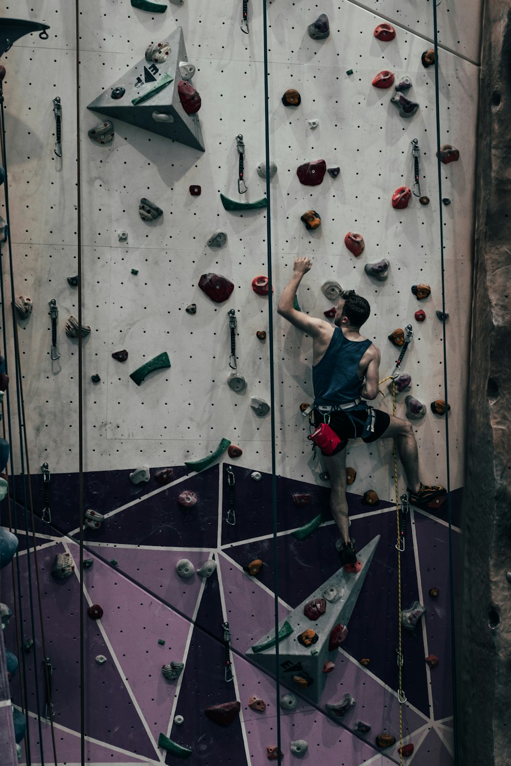 woman in black tank top and blue denim jeans climbing on wall