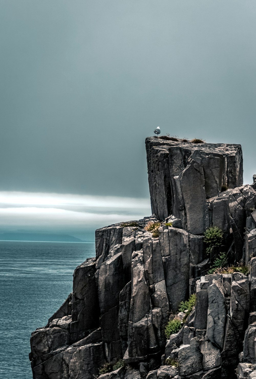 person standing on rock formation near body of water during daytime