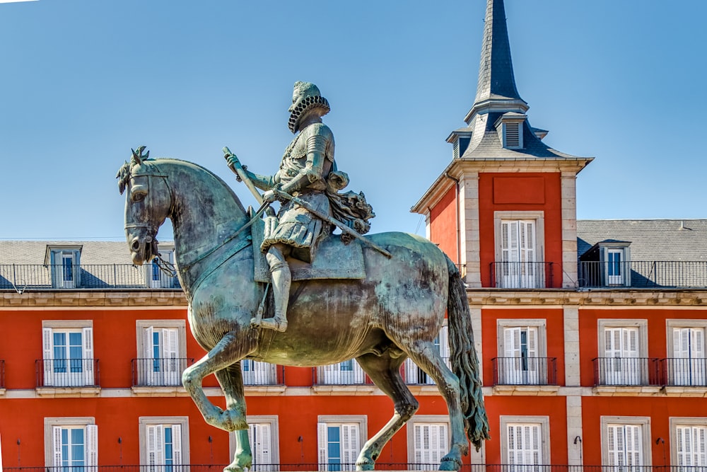 man riding horse statue near brown concrete building during daytime