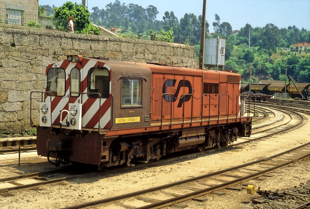 red and brown train on rail tracks during daytime