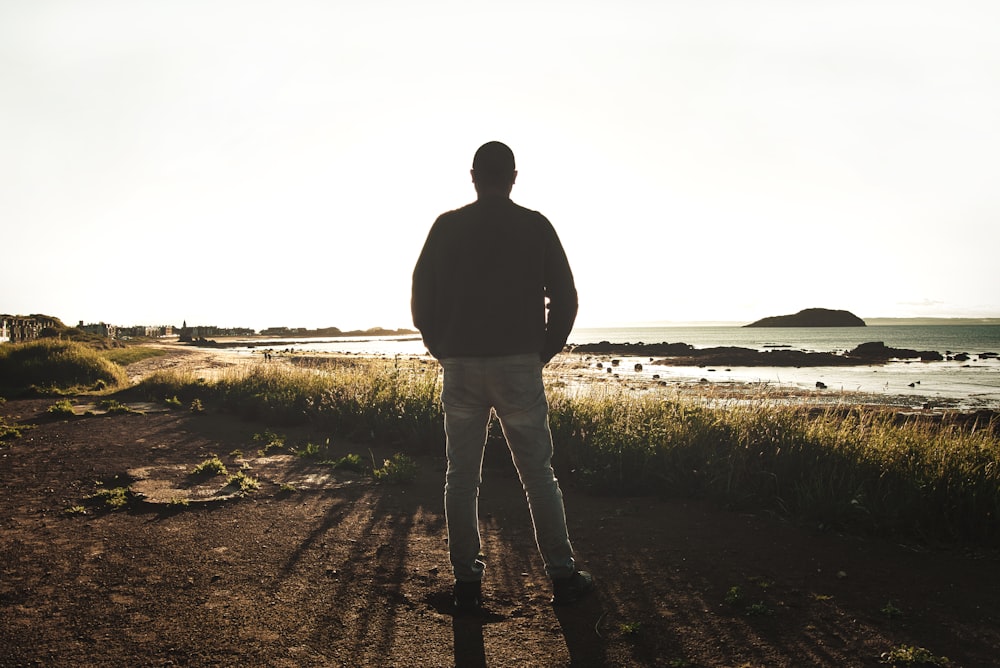 man in black jacket standing on brown field during daytime