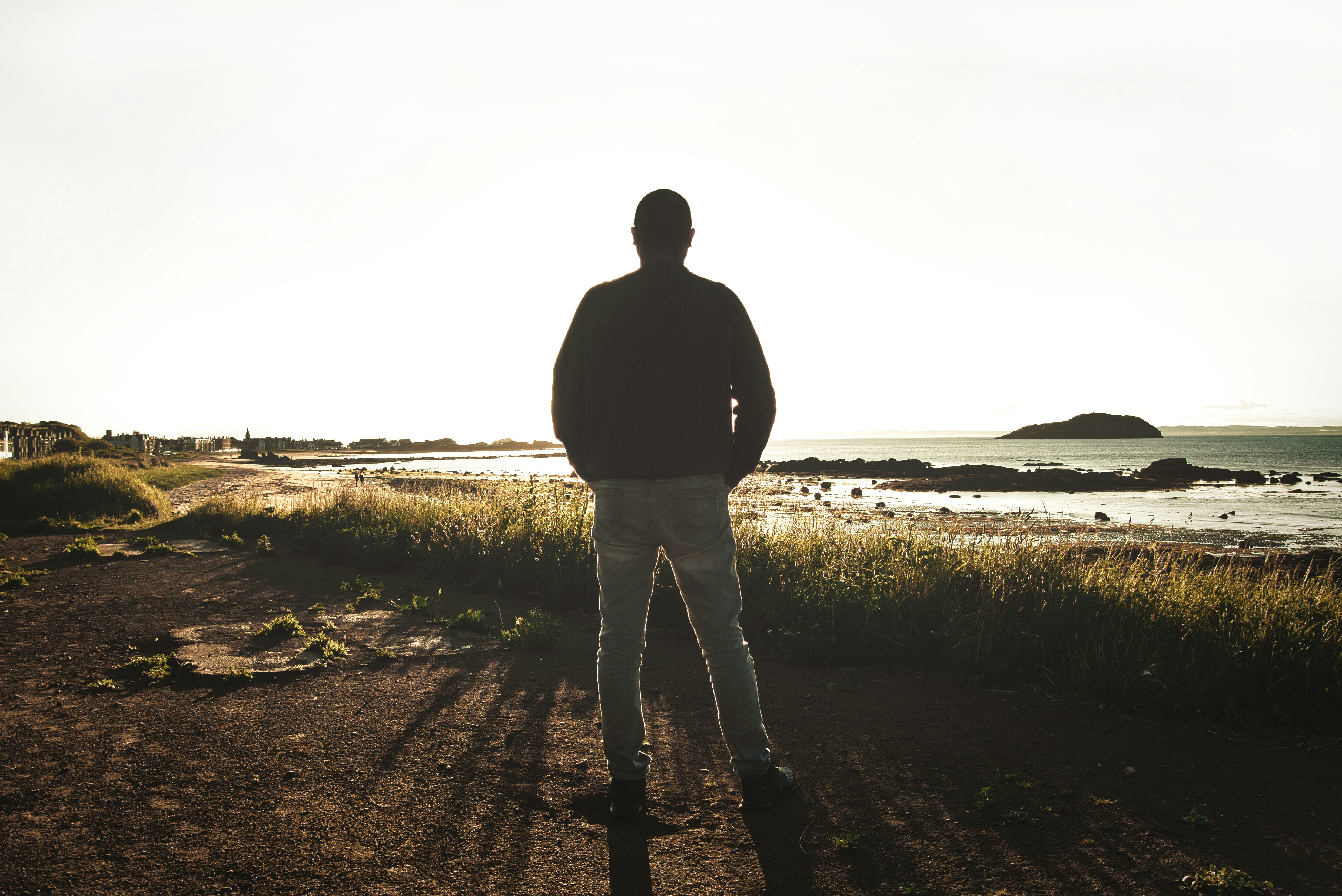 man in black jacket standing on brown field during daytime