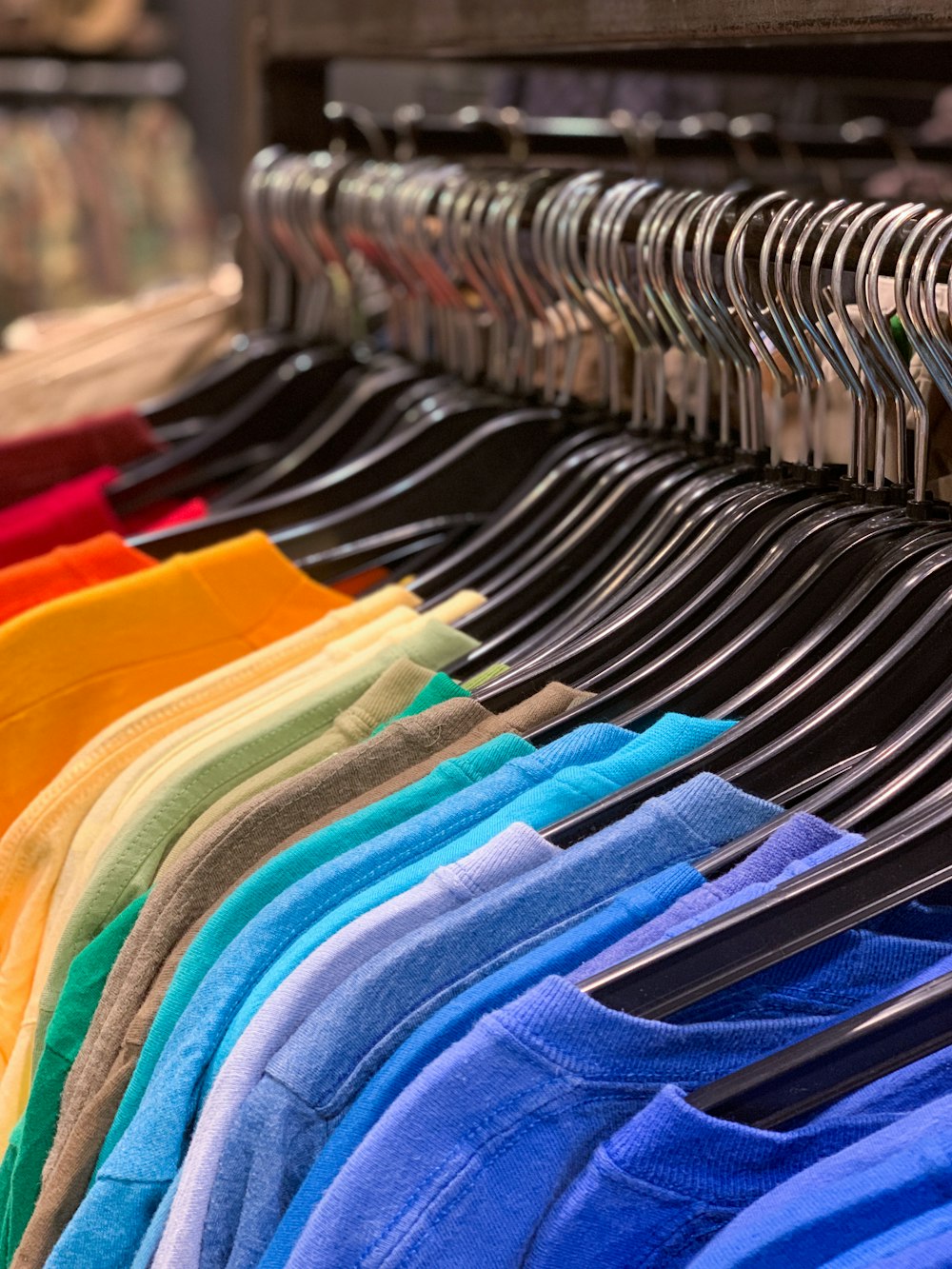 blue red and yellow clothes hanged on black metal rack