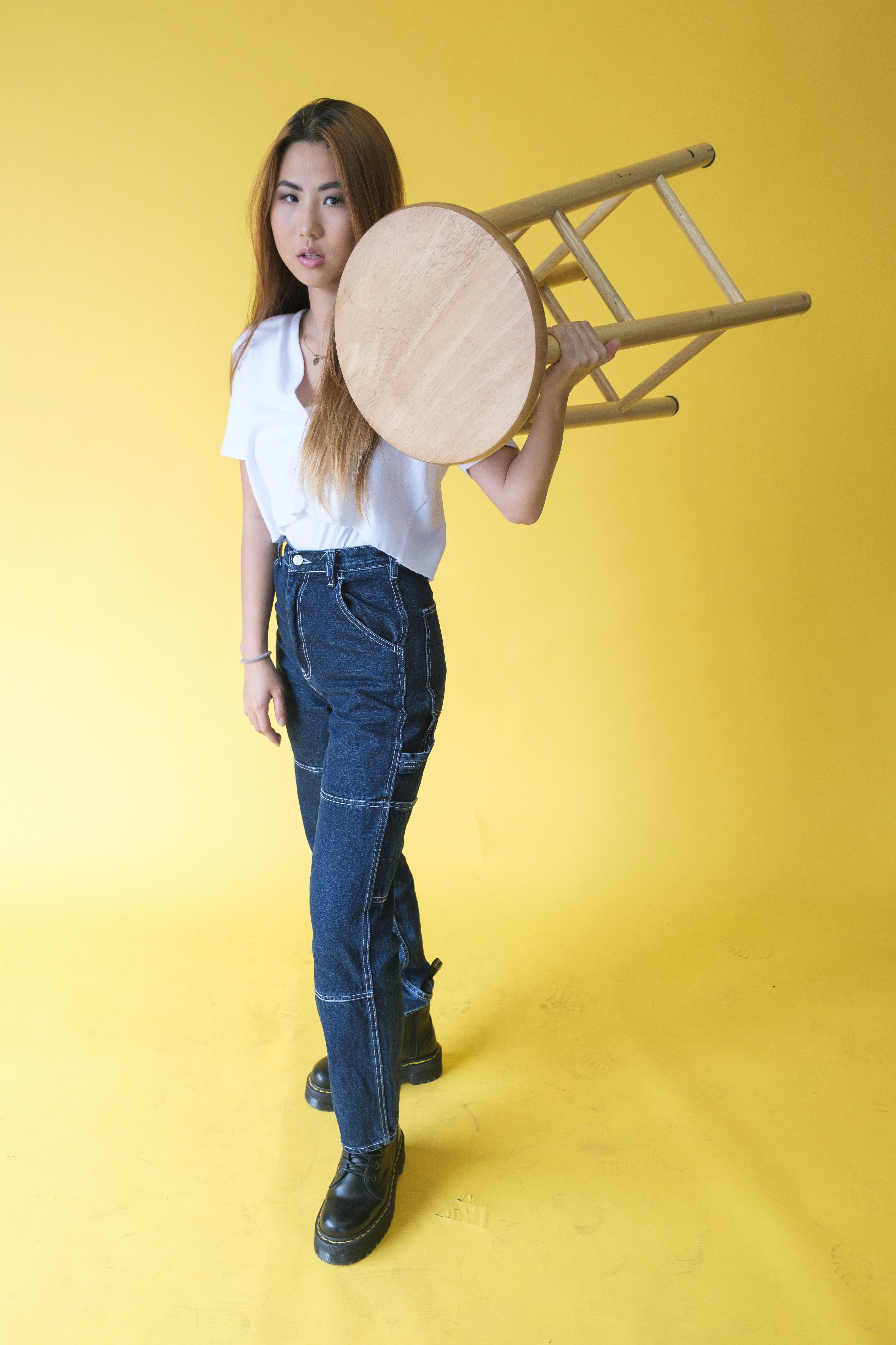 woman in white shirt and blue denim jeans holding brown wooden round board