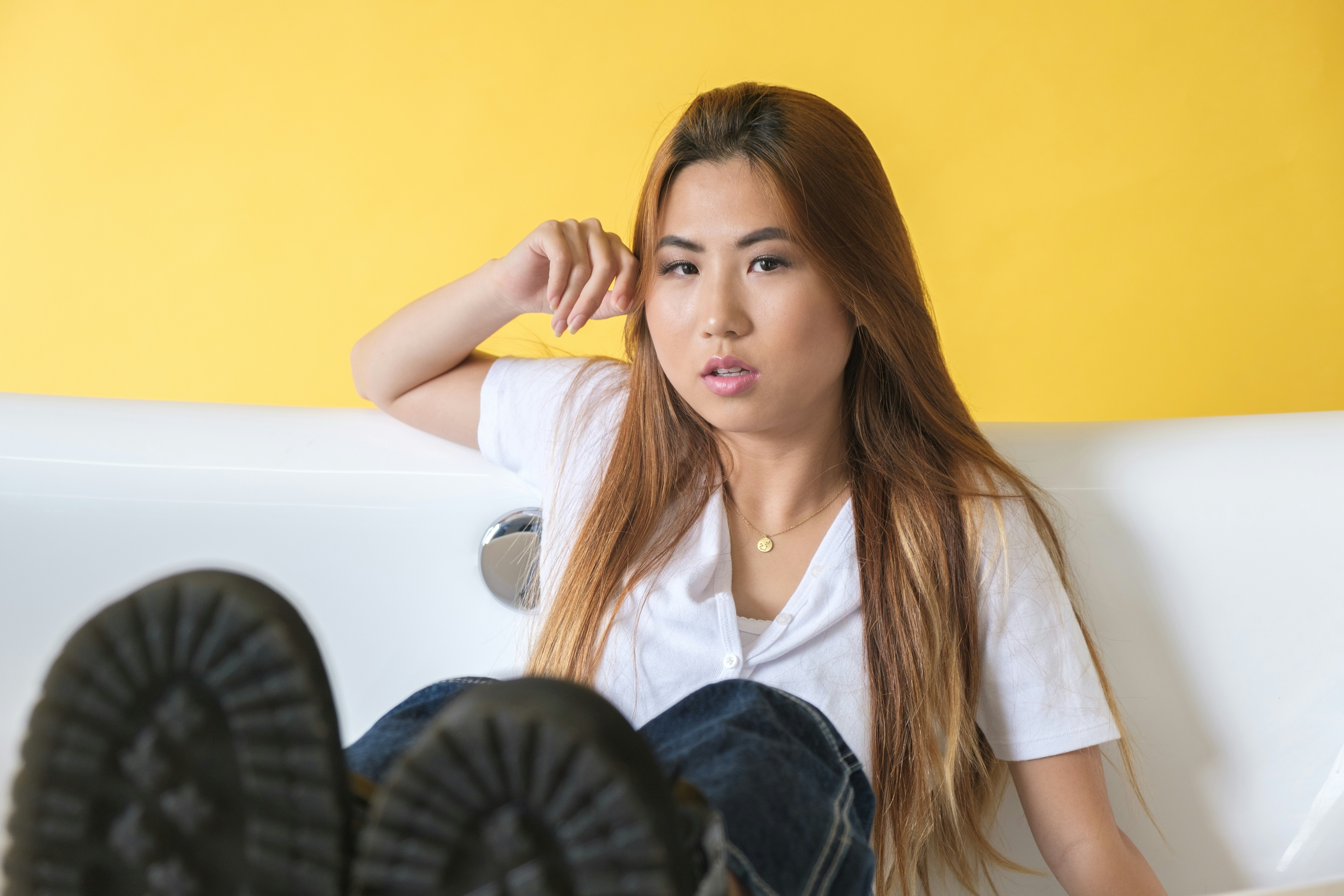 woman in white button up shirt and blue denim jeans sitting on white leather couch