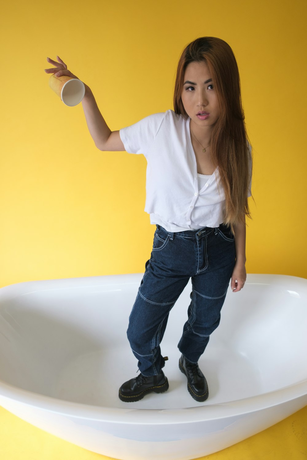woman in white dress shirt and blue denim jeans standing on bathtub