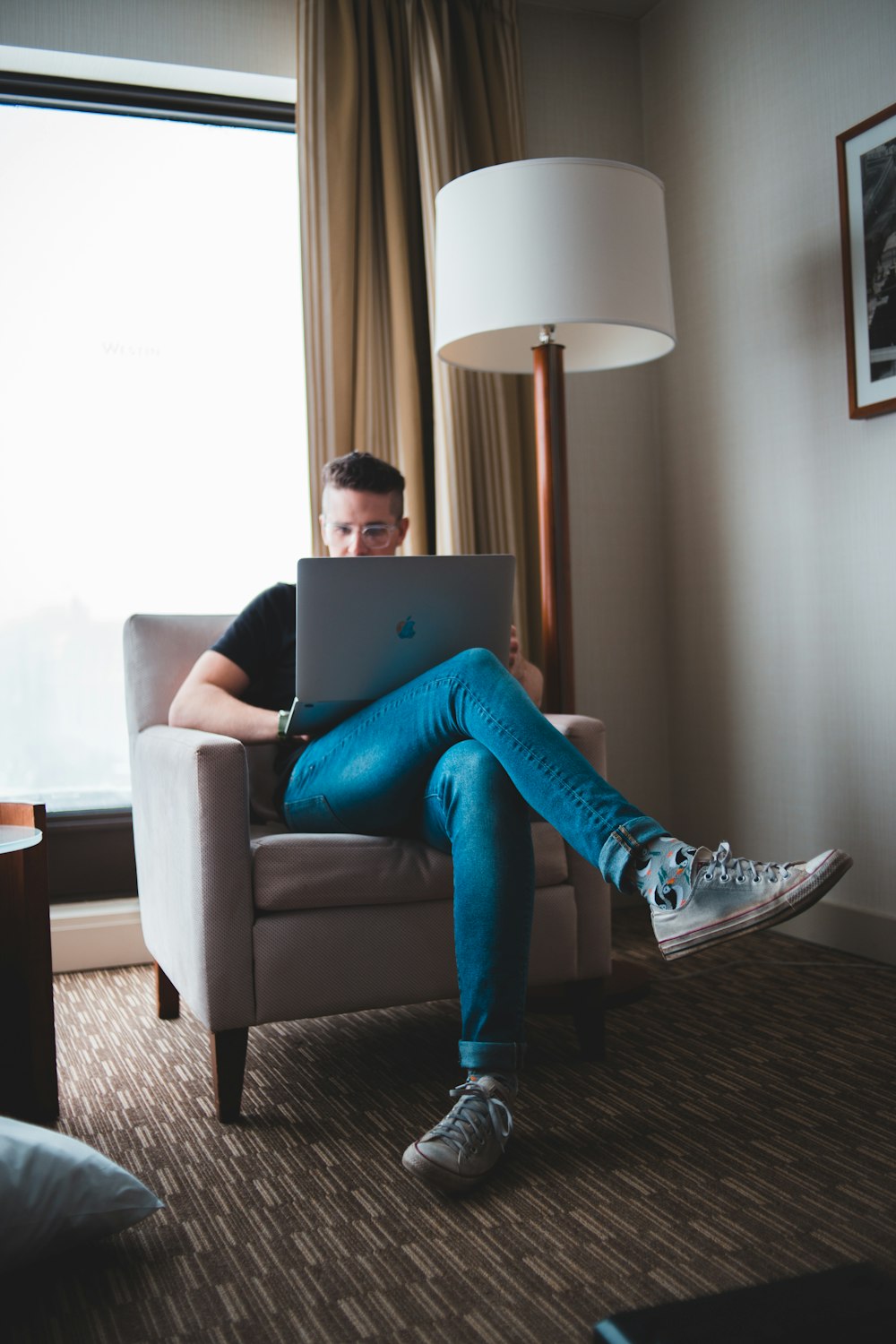 woman in blue denim jeans and black and white nike sneakers sitting on gray sofa chair