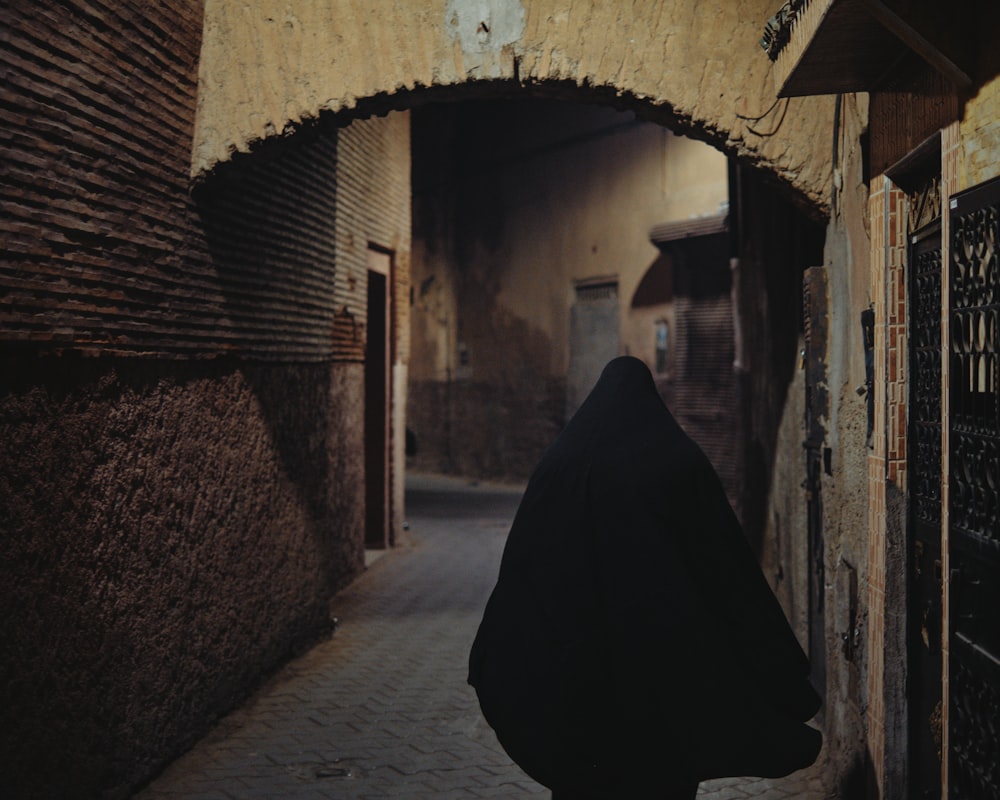 person in black hoodie standing in front of brown brick wall