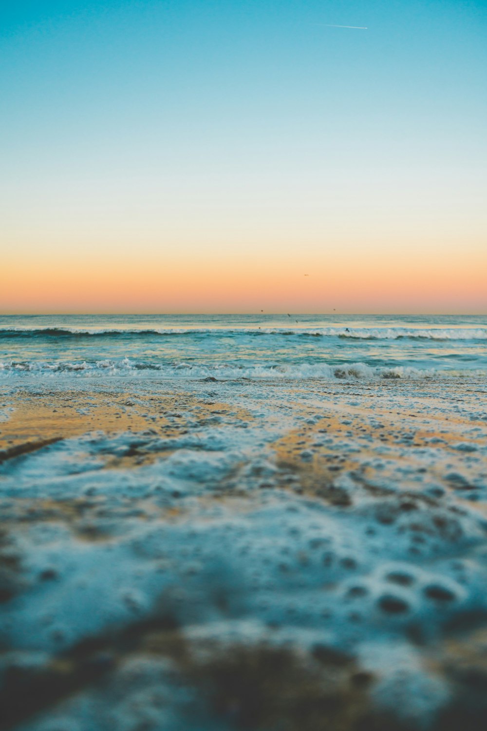 sea waves crashing on shore during sunset