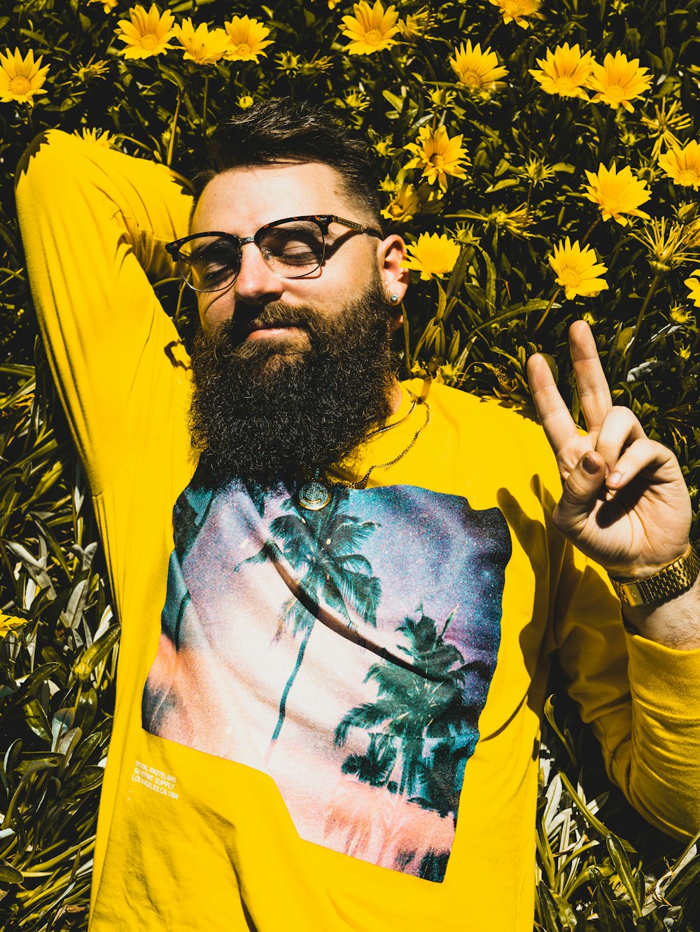 Hombre con camisa floral verde, amarilla y roja con gafas de sol negras