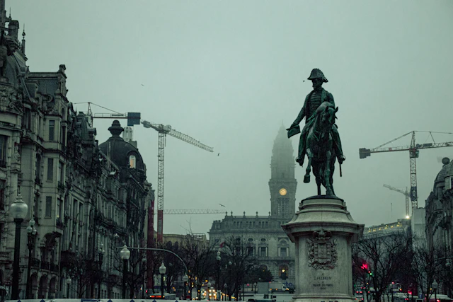 The equestrian statue of King Pedro IV in Praça da Liberdade in fog, with Porto City Hall's tower behind at the foot of Avenida dos Aliados.