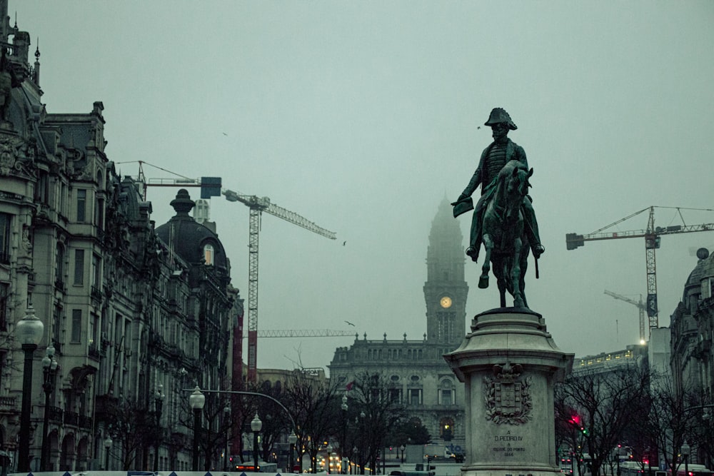 estátua do homem que monta o cavalo perto do edifício durante o dia