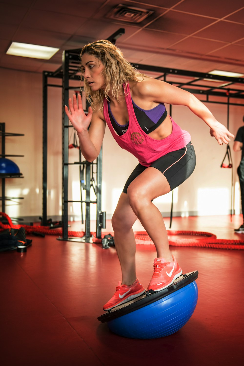 mulher em regata roxa e shorts pretos fazendo yoga