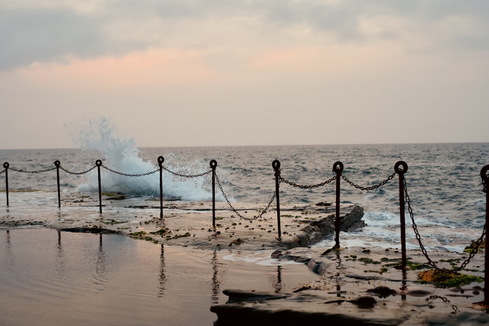 valla de metal negro en la orilla del mar durante el día