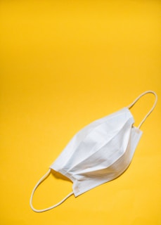A protective mask hanging on a hook against a bright background, highlighting its design details