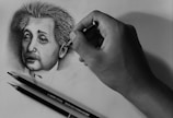 Artist’s hand sketching a detailed pencil portrait on textured paper.