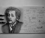 A detailed pencil drawing of a person famous for their theory of relativity, surrounded by various mathematical equations and diagrams related to physics. The drawing showcases detailed facial features and expressions, accompanied by carefully written scientific notes and quotes. Three pencils are placed beside the drawing.