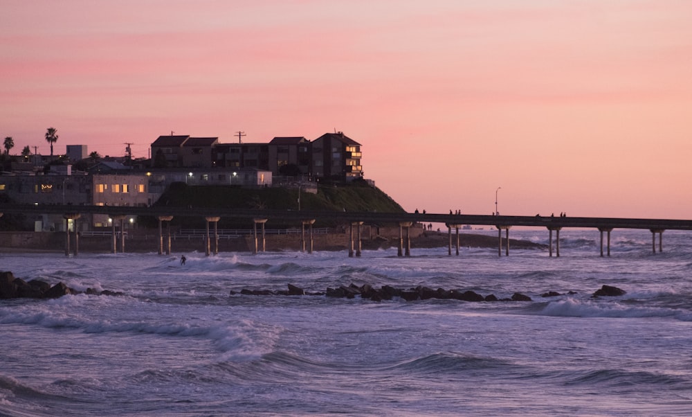 a beach with waves crashing in front of a pier