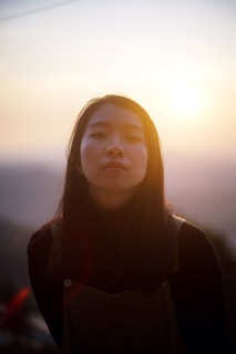 A serene scene of a person gently applying body mist outdoors at golden hour.
