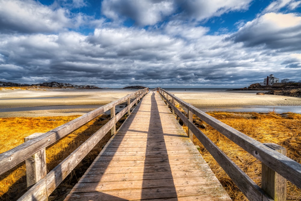 brown wooden dock on beach under white clouds and blue sky during daytime