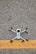 A drone with black propellers is positioned on a textured asphalt surface with a prominent yellow line running horizontally beneath it.