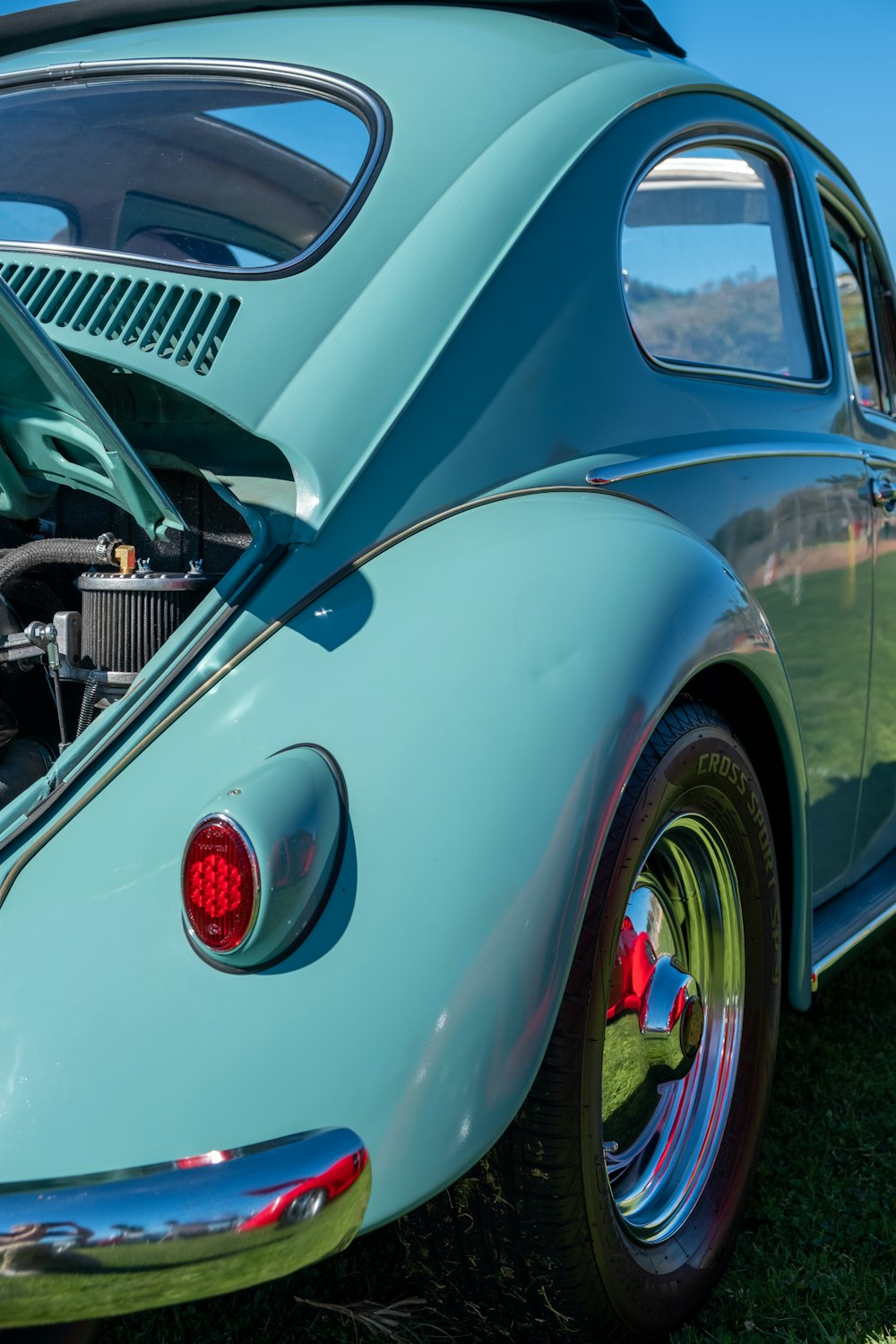 blue classic car with black motorcycle in front