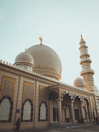 A serene morning view of injii mosque's golden dome shimmering under soft sunlight.