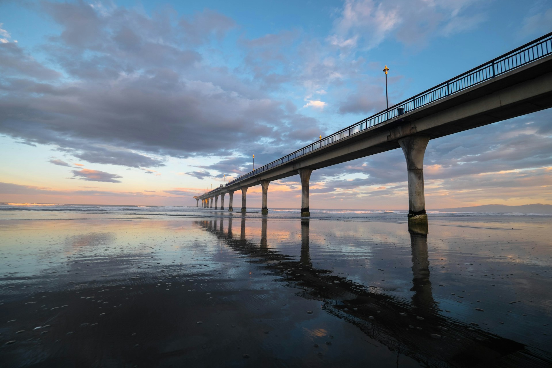 gray concrete bridge over body of water under cloudy sky during daytime