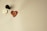 A wax seal with a heart shape and the words 'with love' is stamped on a light-colored surface. A handle, likely part of a seal stamp, rests nearby along with the metal stamp component showing the inverted phrase.
