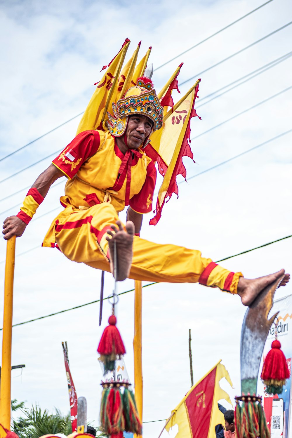 茶色の木の棒を持つ黄色と赤の伝統衣装を着た男性