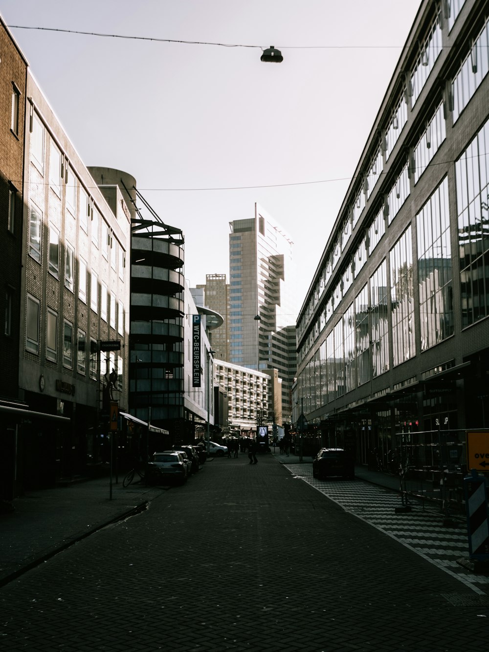 cars parked on side of the road in between high rise buildings during daytime