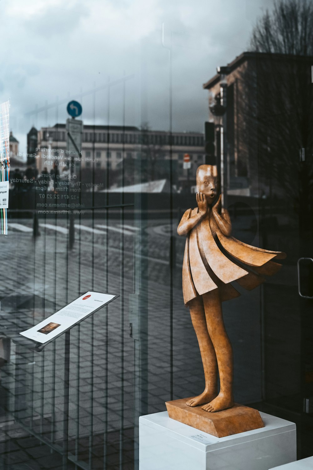 woman in brown coat standing on sidewalk during daytime