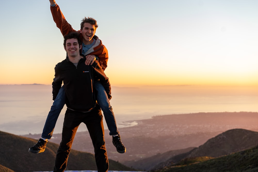 man in black jacket and black pants standing on top of mountain during daytime