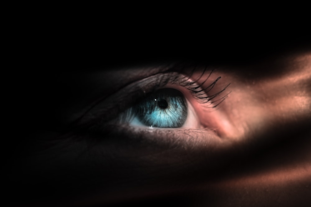 persons blue eye in close up photography