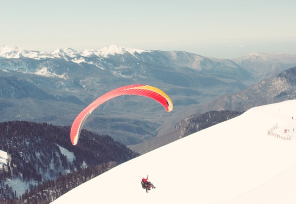 Paraglider over green mountains