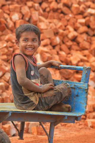 A smiling young boy sitting in a blue cart.