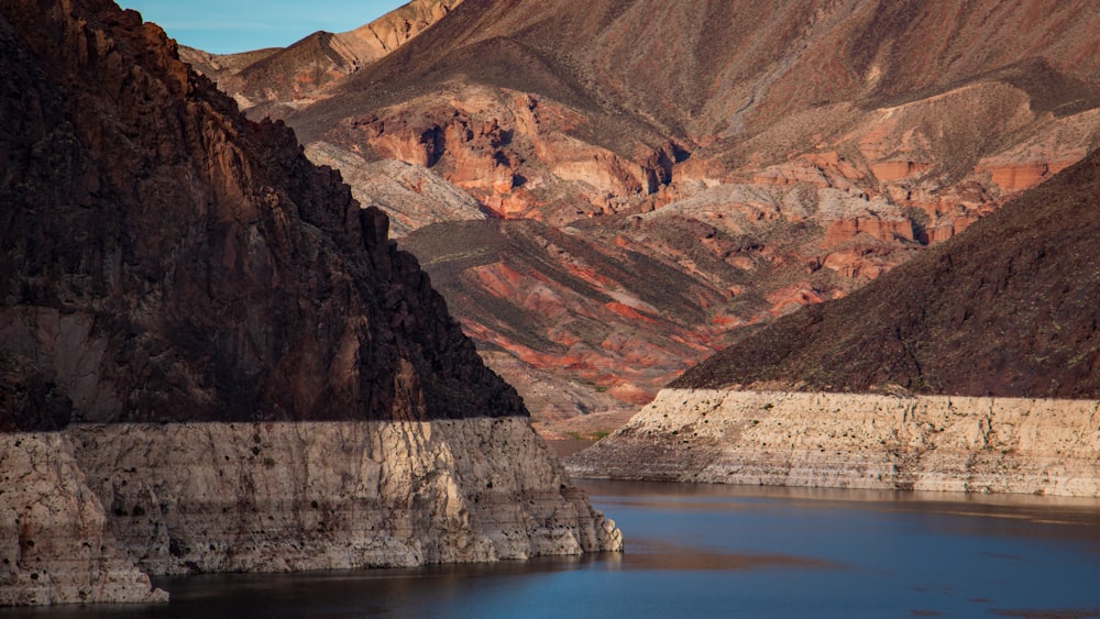 brown and gray mountains beside body of water during daytime