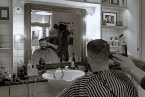 A stylish man getting a precise haircut and grooming in the unisex salon.