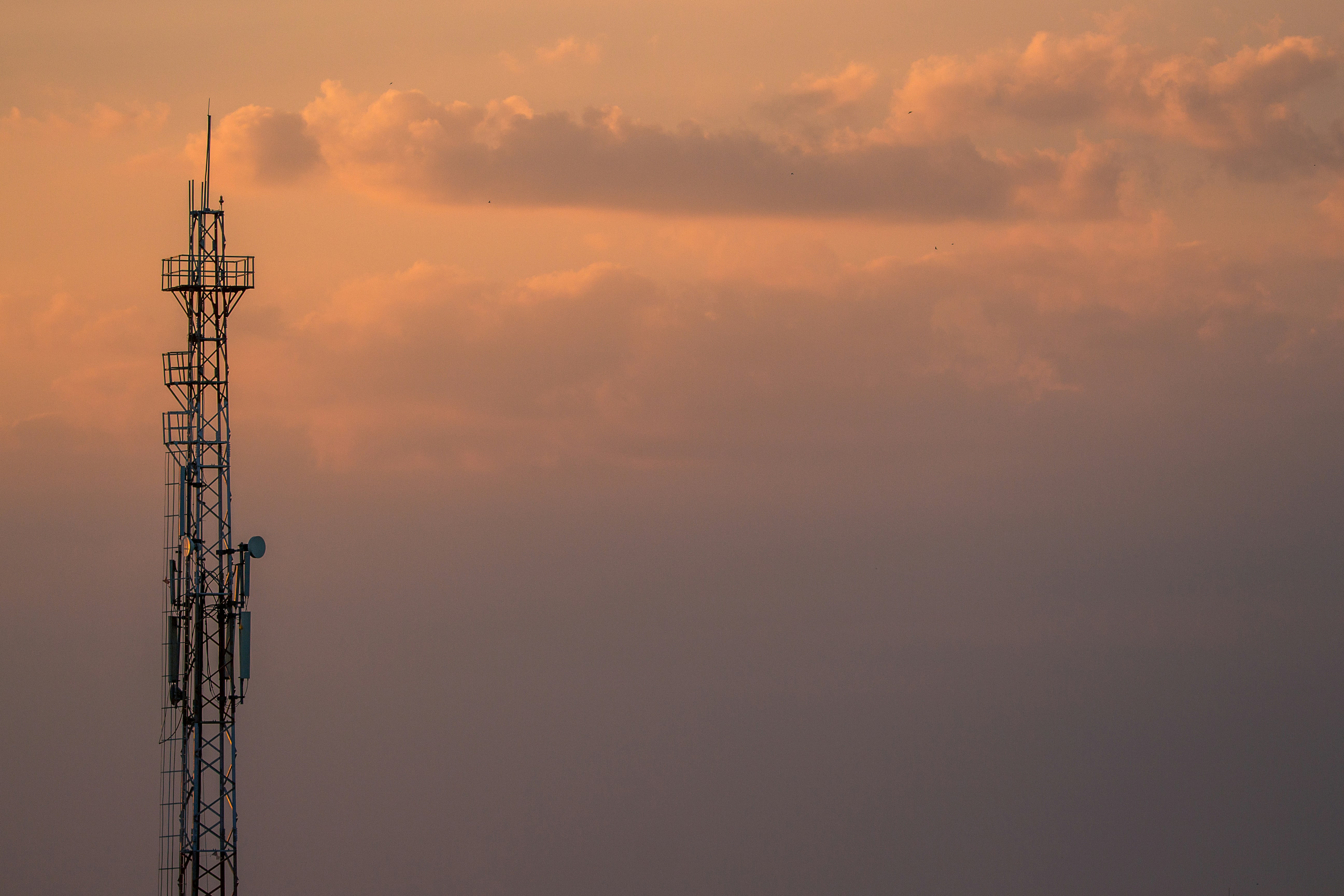 modern telecommunications tower against sky at sunset