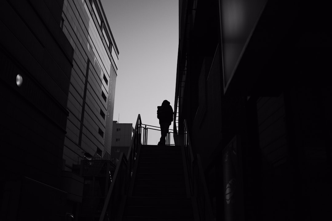 grayscale photo of person walking on stairs