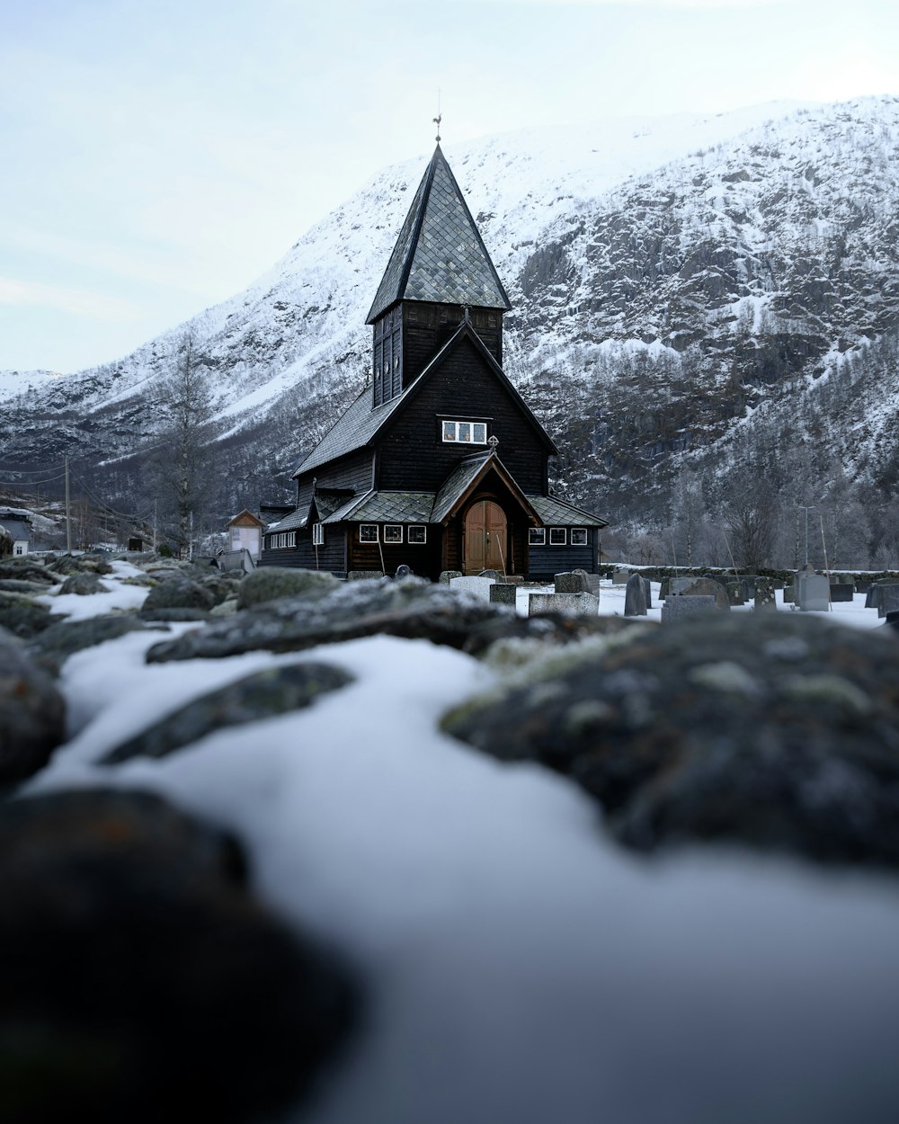 brown wooden house near snow covered mountain during daytime