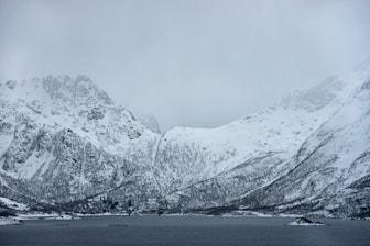 snow covered mountain near body of water during daytime