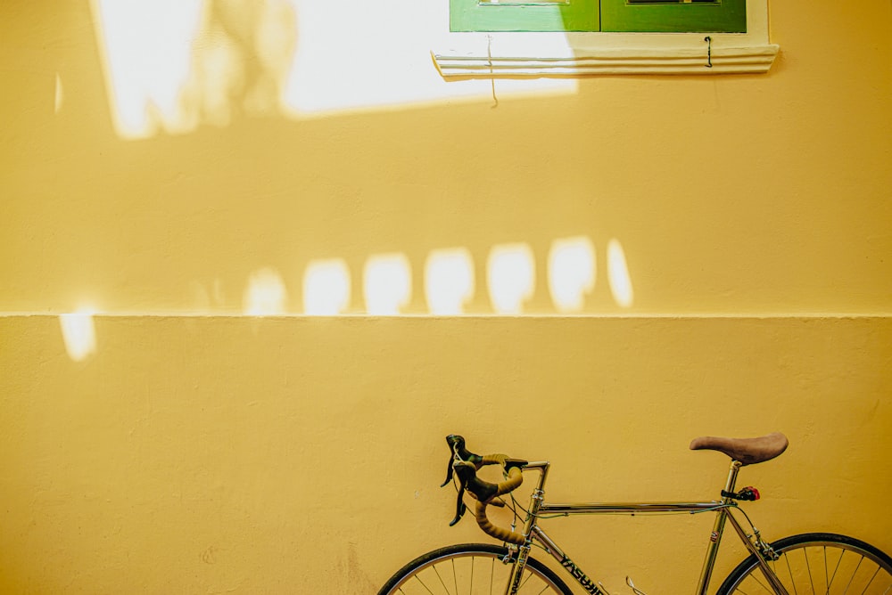 black bicycle parked beside white wall