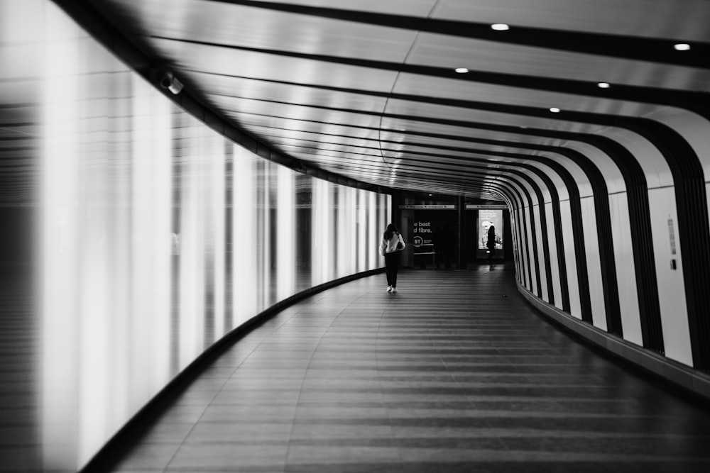 grayscale photo of a woman walking on a hallway