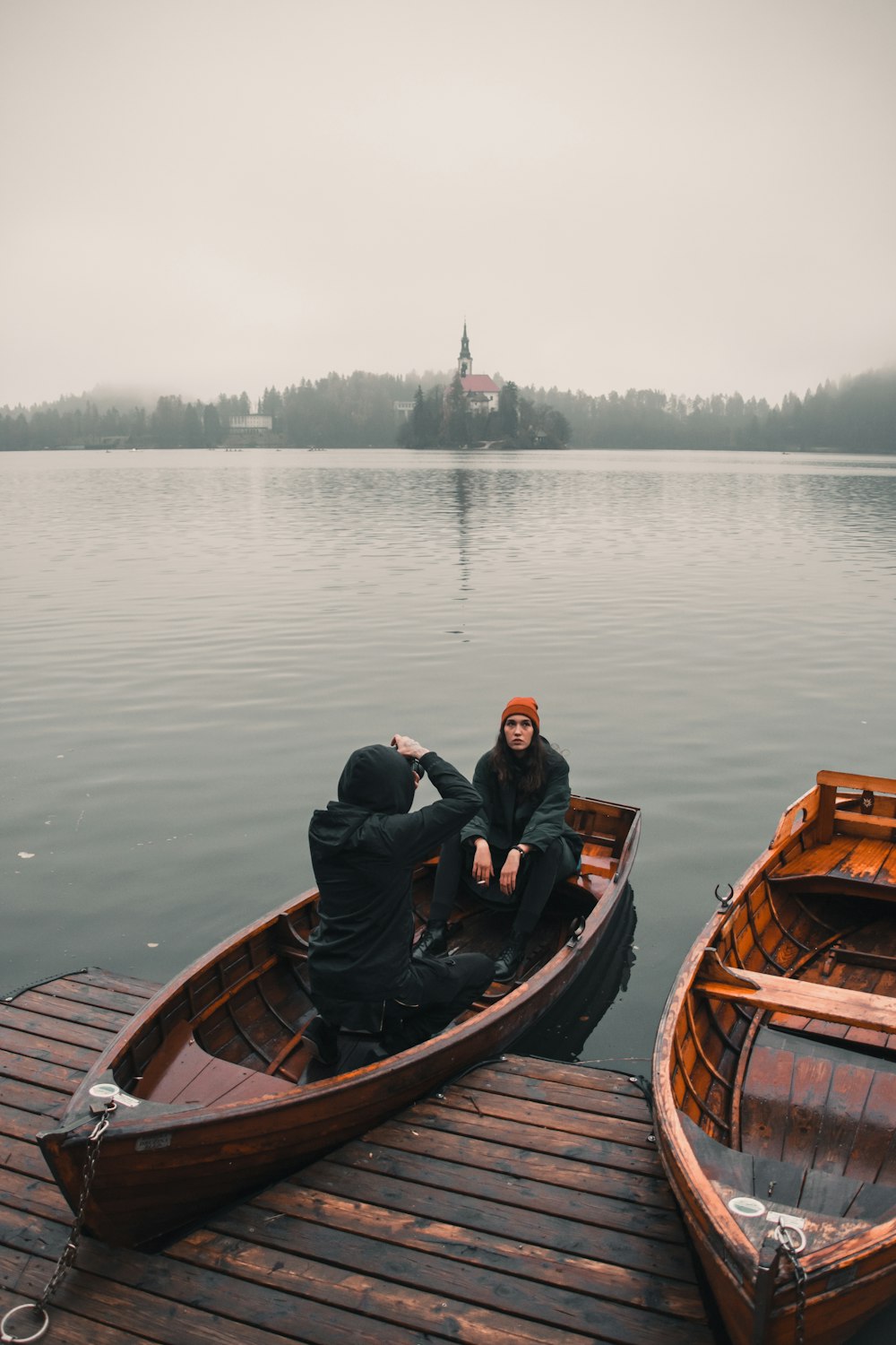 man in black jacket riding brown boat on lake during daytime