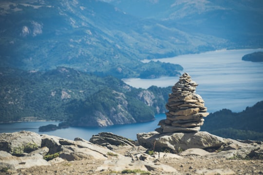 brown and gray rock formation near body of water during daytime in Villa Pehuenia Argentina