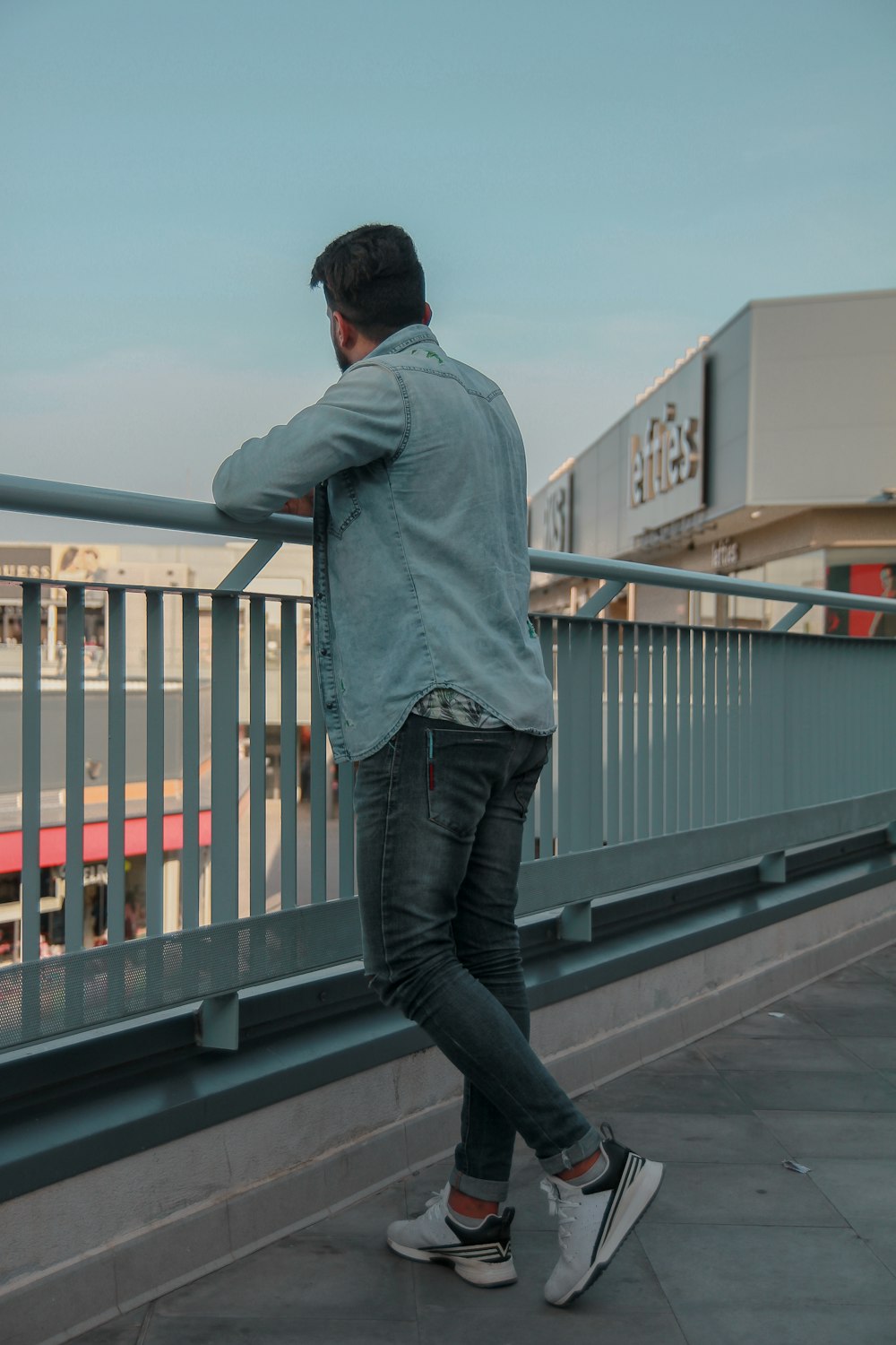 man in gray hoodie and blue denim jeans standing on gray wooden dock during daytime